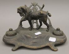 A brass desk stand surmounted with a horse. 26 cm wide.