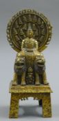 A gilt bronze model of Buddha seated on two dogs of fo. 27.5 cm high.