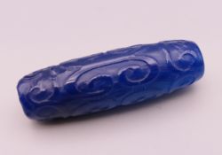 A carved blue bead. 4 cm long.