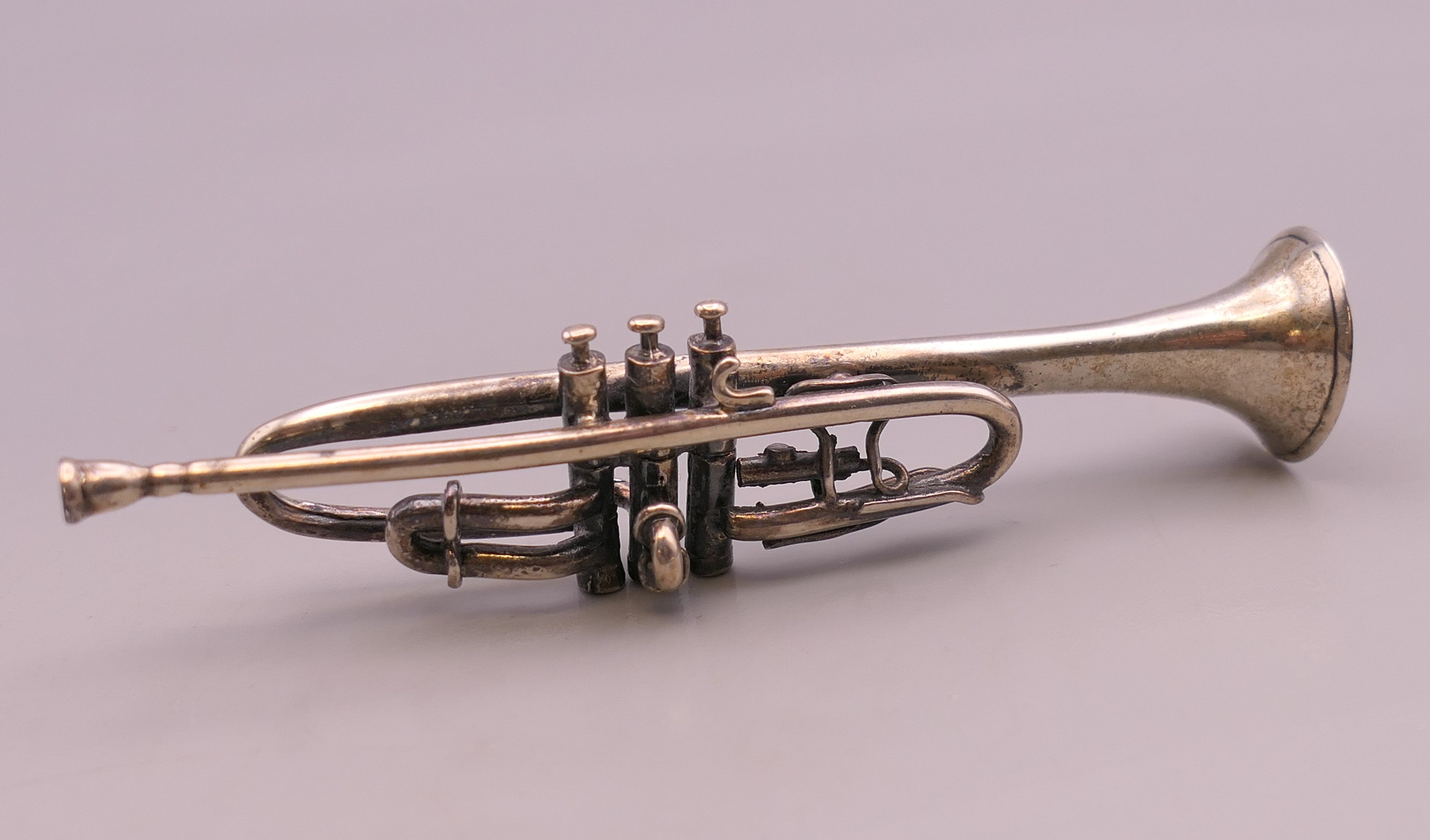 A miniature silver model of a trumpet, hallmarked for London 1993. 7.5 cm long.