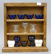 A quantity of eye baths and a set of display shelves.