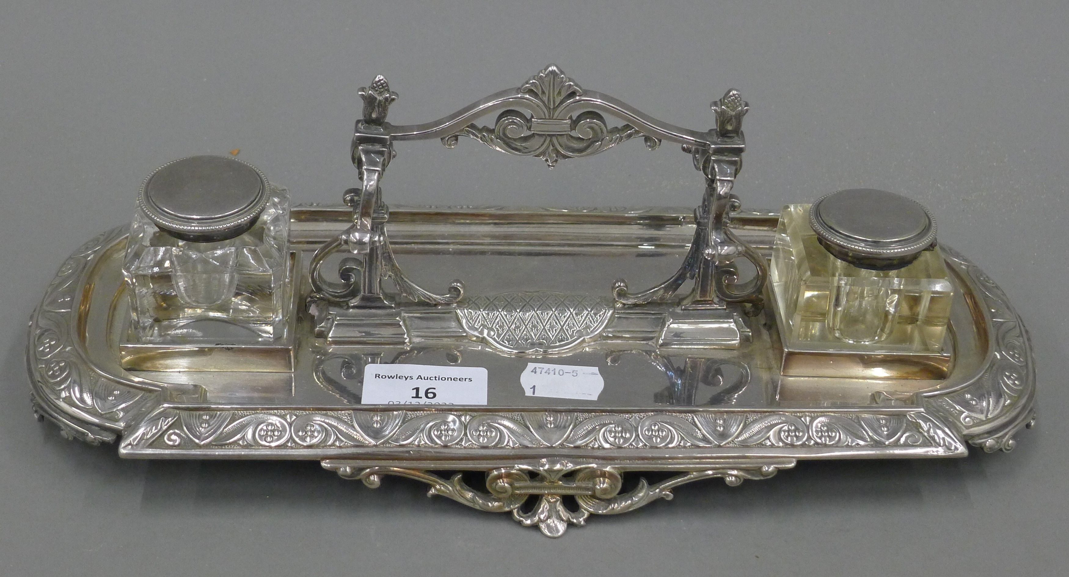 A Victorian silver plated desk stand, with associated inkwells. 32.5 cm long.