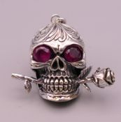 A silver skull and rose pendant. 3 cm long.