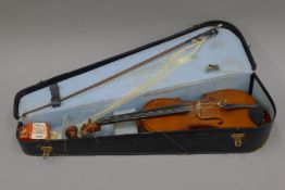 A cased violin and bow. The violin 60 cm long.