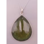 A silver mounted green stone pendant on a silver chain. Pendant 4.5 cm high, chain 44 cm long.