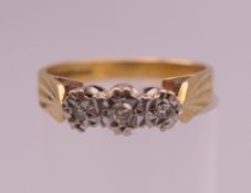 An 18 ct gold three stone diamond ring. Ring size O. 3.5 grammes total weight.