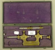 A cased antique brass clock maker's tool. The case 27.5 cm long.