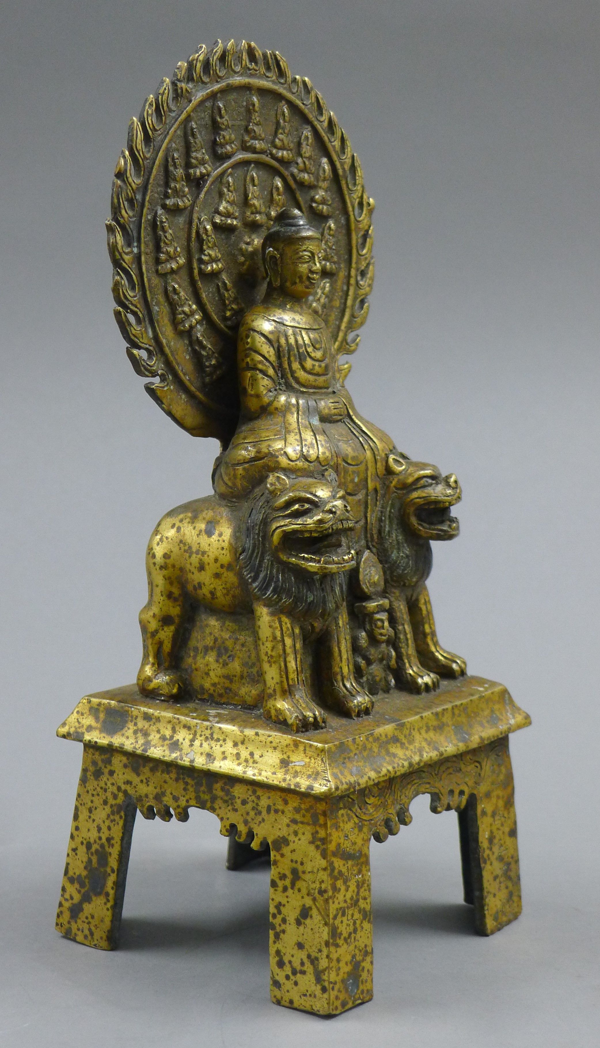 A gilt bronze model of Buddha seated on two dogs of fo. 27.5 cm high. - Image 2 of 4