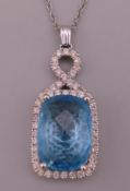 A 14 KT white gold, blue stone and diamond pendant.