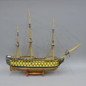 A large handmade wooden model of the 18th century British Warship HMS Victory, on stand. 89 cm long.