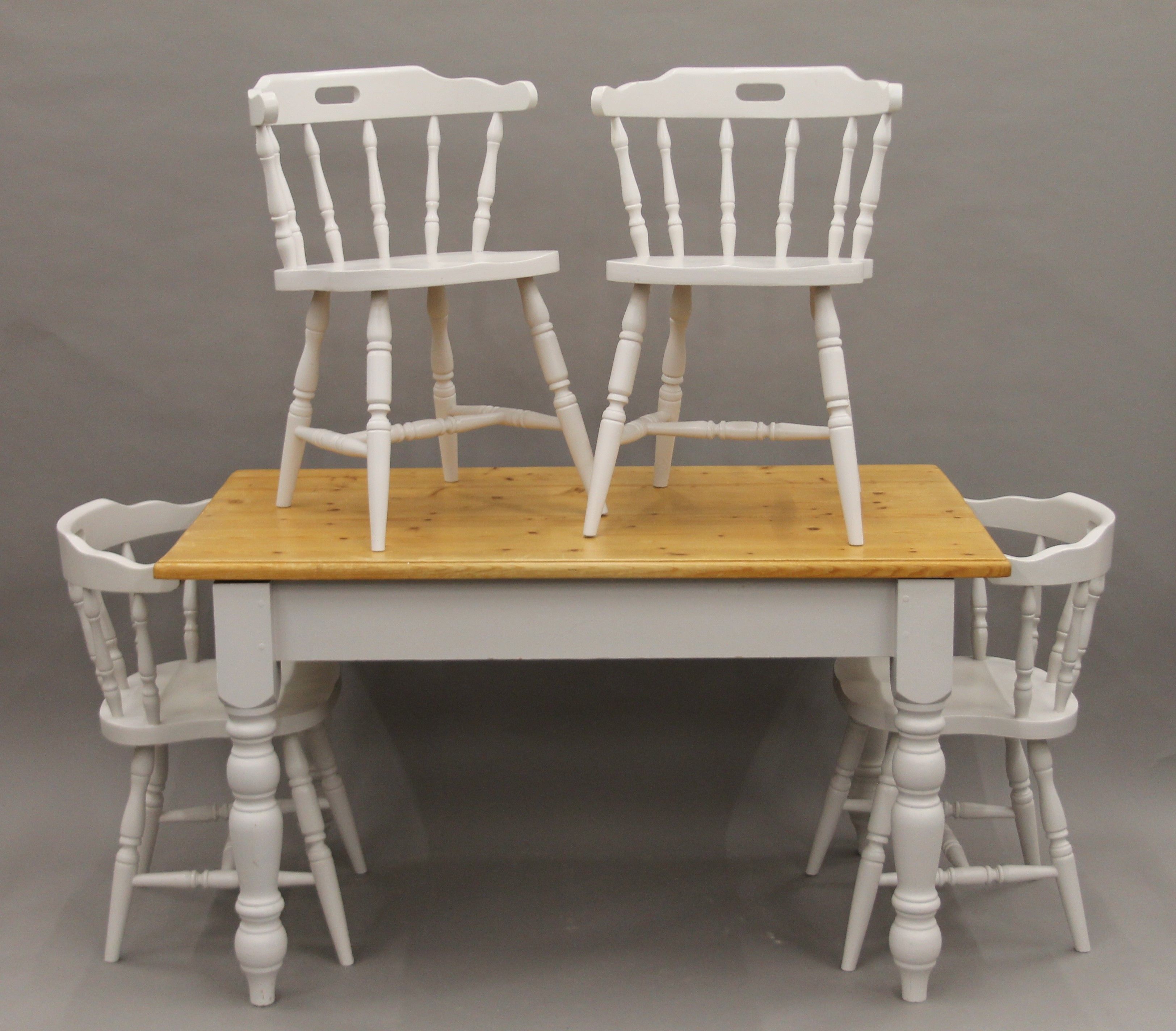 A modern white painted pine table and a set of four modern white painted chairs.