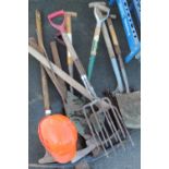 Collection of tools for groundwork including pickaxes, spades, shovels, forks, etc and safety helmet