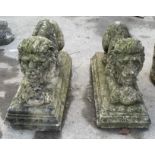 Pair of Regency style weathered composition lions crouching with a ball between front paws, on