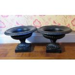 Pair of small black painted cast iron campana shaped urns, on lobed supports and square bases, D39cm