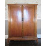 C20th Chinese hardwood side cabinet the two paneled doors with loop handles enclosing three shelves,