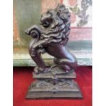 Early C20th cast iron door stop in the form of a Heraldic lion, seated with scroll support on