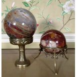 Two polished agate spheres, one on openwork tripod frame, the other on brass cup stand, H7cm max (2)