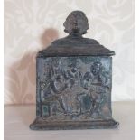 C19th lead square tobacco box, stepped cover with four faced mask head finial, the sides decorated