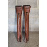 Two early C20th tan leather gun cases, tapering bodies with cover and brass buckle