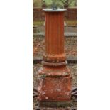 Green verdigree metal sun dial on fluted terracotta column with stepped circular base on square