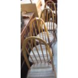 Set of four light elm Ercol stick back dining chairs with loose padded seats (one A/F)