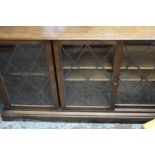 Oak two tier low bookcase enclosed by three sliding lead glazed doors H134cm W26cm D75cm