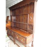 Late c18th oak dresser with moulded and dentil cornice, open shelves flanked by two fielded panelled