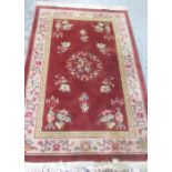 C20th Chinese style thick woolen rug, inset floral patterns on a raspberry red ground, with cream