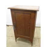 Early C20th oak single door cupboard with over hanging top, single panel door on square tapering