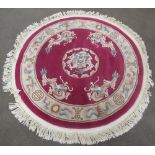 C20th circular Chinese embossed washed woolen rug, claret ground with central dragon motif
