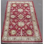C20th Turkish traditional pattern wool rug, central red field set with floral motifs, surrounded