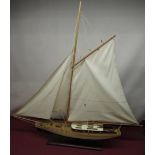 Large model yacht with cream and black painted hull on wooden stand, H89cm