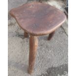 Rustic made oak stool, the naturistically shaped top on three rough hewn legs, W27cm D40cm H56cm