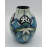 Moorcroft pottery vase c2009 in a tube lined pattern of white flowers on blue green background,