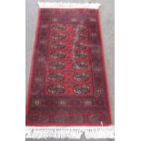 Late C20th traditional Bokhara pattern wool rug, red ground with central medallion set centre and