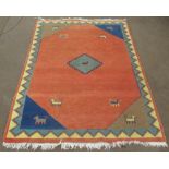 C20th Indo Persian wool rug, brick red ground with central medallion set with stylized animal, field