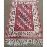 C20th Middle Eastern rug, beige and brick red ground with central field set with multiple