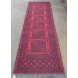 C20th traditional pattern wool runner, red ground with six central geometric pattern medallions,