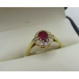 Hallmarked 18ct yellow gold diamond and ruby cluster ring with central oval cut ruby, ten round