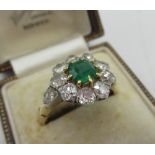 Diamond and emerald cluster ring with central cushion cut emerald, a halo of ten round cut
