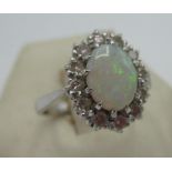 Hallmarked 18ct white gold ring with central oval opal and a halo of twelve round cut diamonds, by