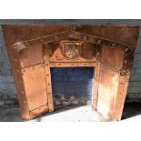 C20th beaten copper fire insert, the angular arched recess with heraldic lion cresting, W99cm