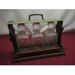 Early C20th oak three bottle tantalus with metal fittings
