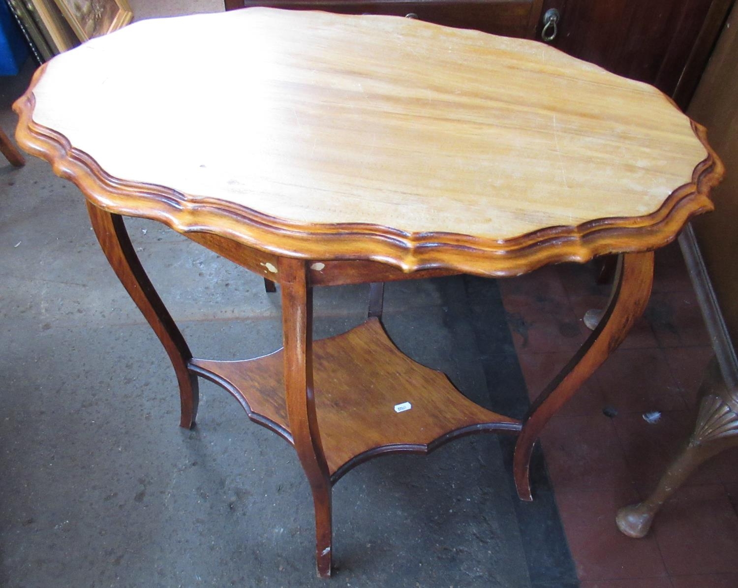 Edwardian walnut two-tier occasional table, with pie crust edge oval top on angular cabriole