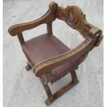 Continental Savonarola type chair, back carved with a warrior head, brass nailed fringed leather