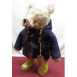 Paddington Bear soft toy wearing yellow boots and a navy duffle coat, with glass eyes and plastic