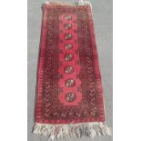 C20th Caucasian patterned red ground runner, centre set with eight octagonal medallions surrounded
