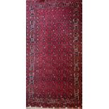 Herez pattern red ground wool rug with central field with geometric motifs, stylised striped border,