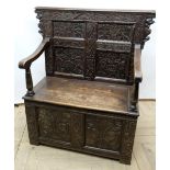 C20th oak settle, raised scroll work back with four earlier carved and initialled panels, moulded