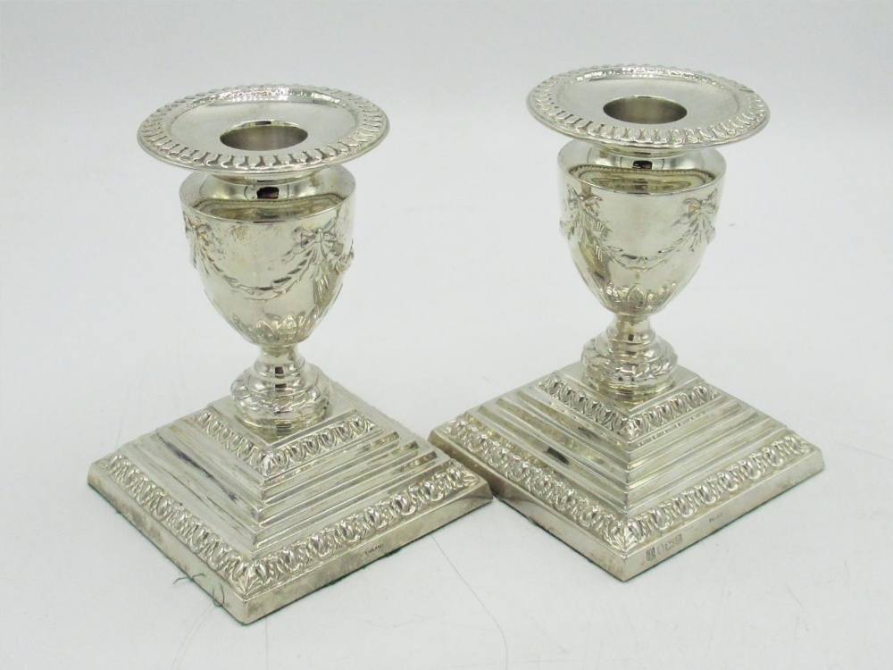Pair of Geo.V hallmarked sterling silver candlesticks, urn shaped sconces relief decorated with bows